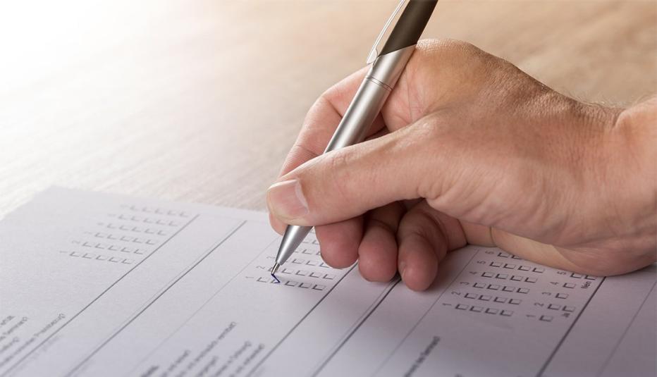 close-up of hand answering questions on poll sheet